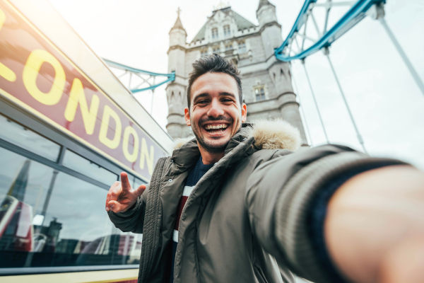 hombre sonriente sacando una selfie durante sus viajes a Londres, Inglaterra.