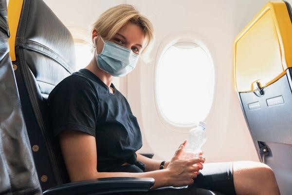 Mujer usando mascara protectora dentro de un avión