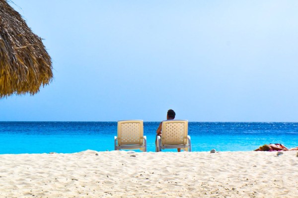 imagem de pessoa sentada em cadeira de praia em uma praia de Curaçao