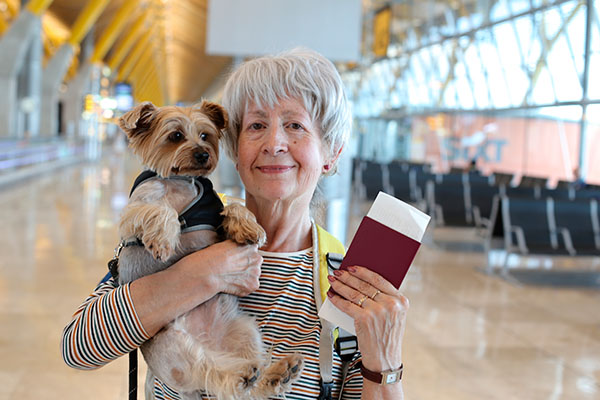Mujer adulta en el aeropuerto sosteniendo un pasaporte y un perro