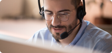 Um homem de óculos e fone de ouvido trabalhando em um computador.