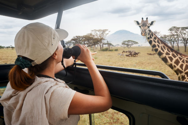 Turista mujer observando a una jirafa durante un safari en Kenia.