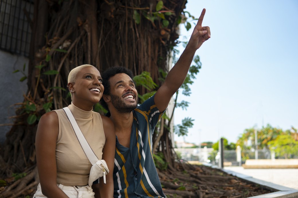 Casal sorridente, composto por homem e mulher, em cenário ao ar livre durante viagem para a África do Sul