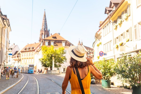 Mujer turista pasando por el Ministerio de Friburgo en la ciudad de Friburgo de Brisgovia, Alemania.