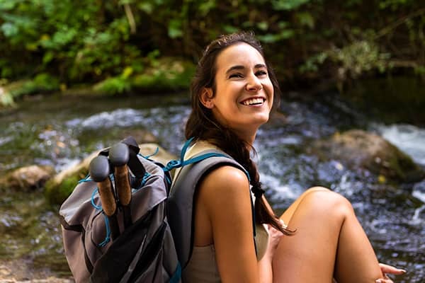 Mulher sorrindo sentada na beira da cachoeira