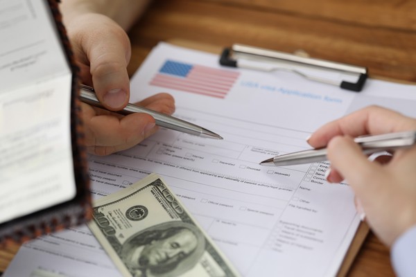 Proceso de solicitud de visa estadounidense en papel con vista de pasaporte y billete de 100 dólares para la tasa consular