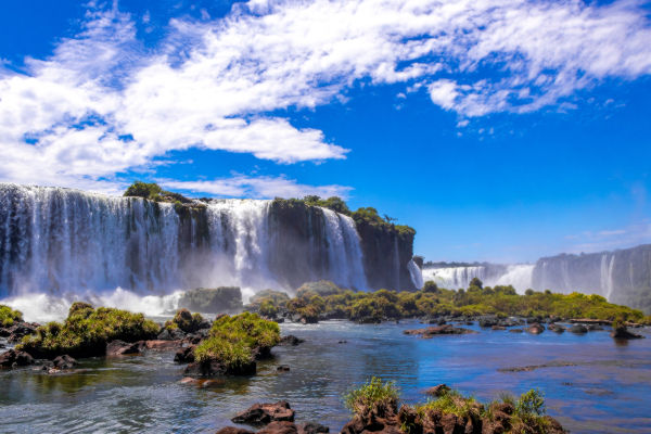 Cataratas del Iguazú en un día soleado, rodeadas de vegetación y cielo despejado.