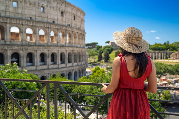 Chica con sombrero y vestido rojo mirando Coliseo romano