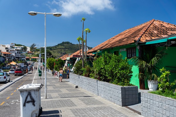 Vista sur de la avenida Dr. Hermes Barcelos con pequeños edificios frente a la playa de Praia Grande en verano, pueblo de Arraial do Cabo, Brasil.