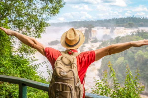 Turista con mochila disfrutando la vista panorámica de las Cataratas del Iguazú.
