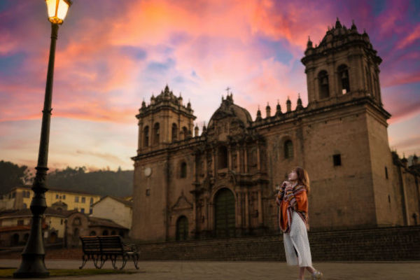 Turista admirando la Catedral de Cusco al atardecer, durante su viaje por Perú.