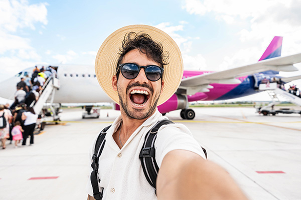Turista tomándose una selfie con un avión de fondo