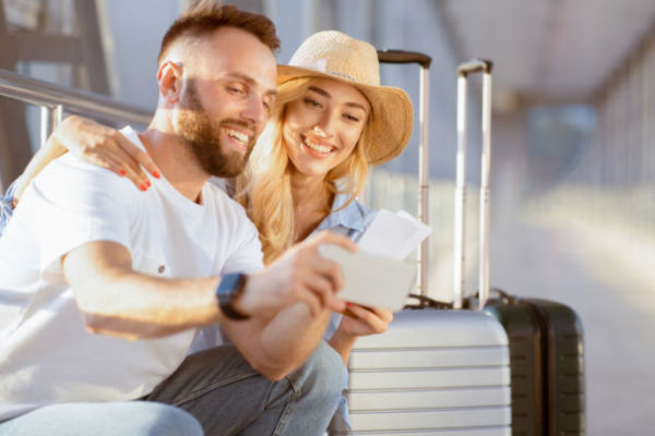 Pareja sonriente sentada con sus maletas, lista para viajar y comenzar el año con energía.