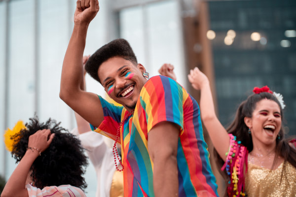 Hombre sonriente bailando en un Carnaval en Brasil con ropa y maquillaje colorido.