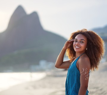 Mujer posando para la foto en la playa de Ipanema, Río de Janeiro, Brasil, con montaña al fondo.
