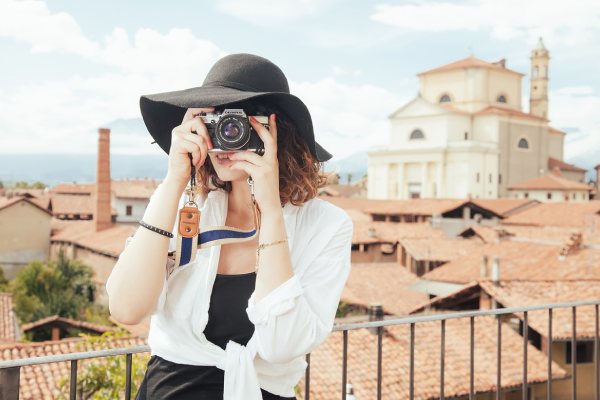 imagem de mulher tirando foto, observando em câmera fotográfica, para falar sobre seguro viagem para a espanha