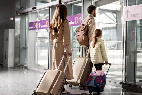 magem de família composta por homem, mulher e uma menina com malas em um aeroporto, representando viagem aos estados unidos com seguro viagem eua. A Assist Card proporciona seguro também às bagagens