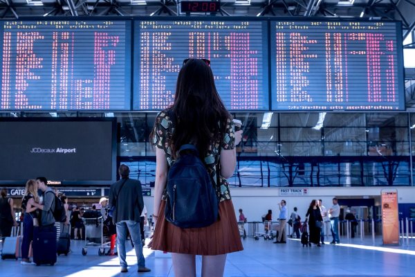 imagem de uma mulher, de costas, em um aeroporto para falar sobre viagens nos feriados 2025