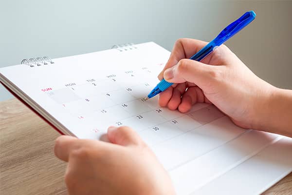 una mano escribiendo sobre un calendario