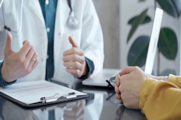 Médico atendiendo a una viajera en una clínica, mientras ella muestra su tarjeta de asistencia al viajero.