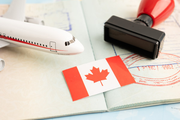 Bandera de Canadá sobre pasaporte con sello y avión en miniatura.