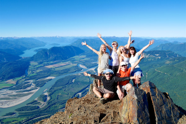 Grupo de amigos alzando los brazos en la cumbre del Monte Cheam, Columbia Británica, Canadá.
