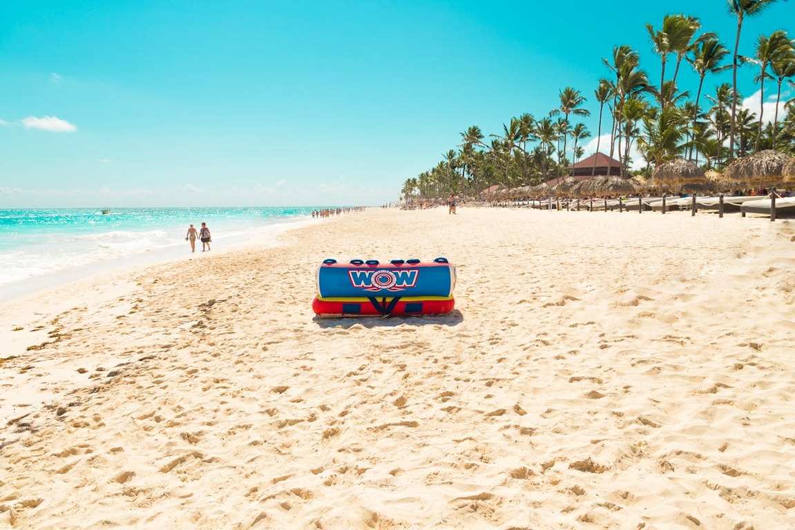 Imagem de praia paradisíaca com areia clara, águas tranquilas e azuis e coqueiros, ilustrando artigo de blog sobre como escolher entre Cancún ou Punta Cana.