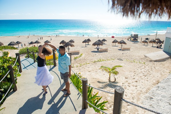 Pareja bailando en la bajada a una playa en Cancún.