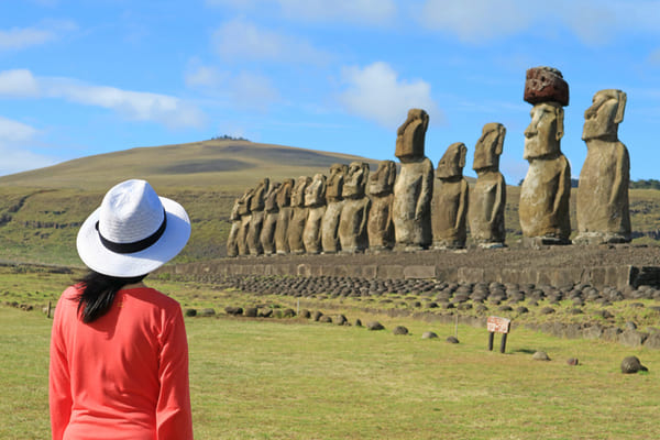 Mujer visitando las icónicas quince estatuas Moai de la plataforma ceremonial Ahu Tongariki en Isla de Pascua, Chile
