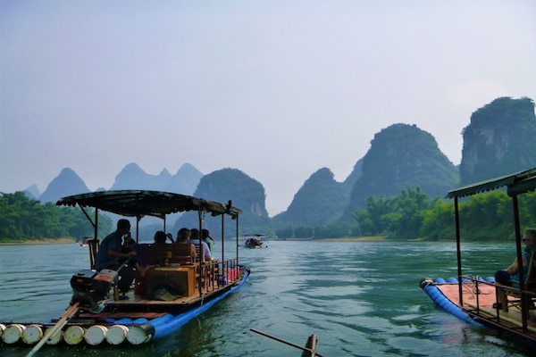 Barcos turísticos sobre o rio Guilin, com formações rochosas ao fundo, na China.