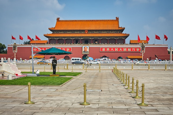 Vista da Praça Tiananmen em Pequim, na China, com guarda e carros transitando na avenida.