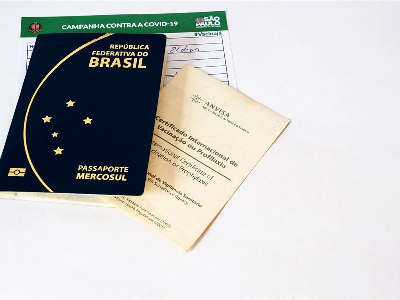 Passaporte e um certificado internacional de vacinação contra febre amarela dispostos sobre uma mesa, documentos obrigatórios para a entrada em diversos países.