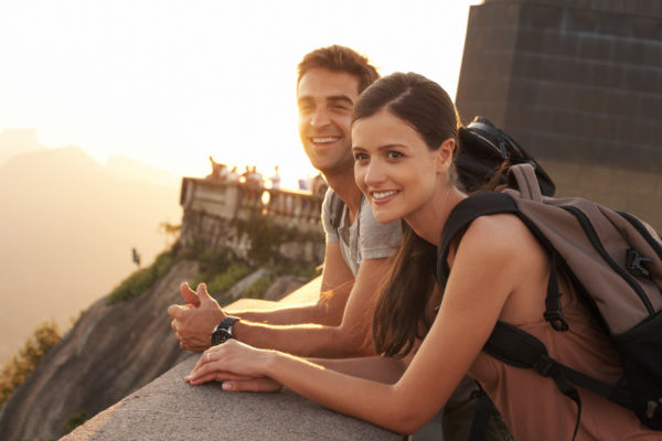 Pareja de turistas sonriendo en un mirador de Río de Janeiro al atardecer.