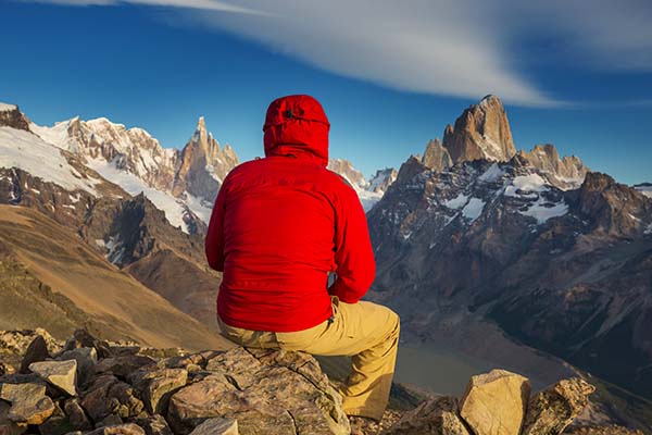 Hombre sentado en una piedra observando las montañas de la Patagonia.