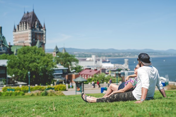 Hombre y mujer embarazada descansando en el césped de un parque en la ciudad de Québec, Canadá.