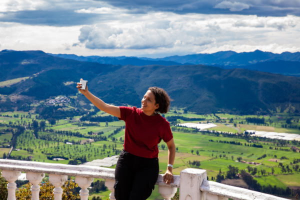 Viajera tomándose una selfie con vista panorámica de montañas y valles verdes en el interior de Colombia.