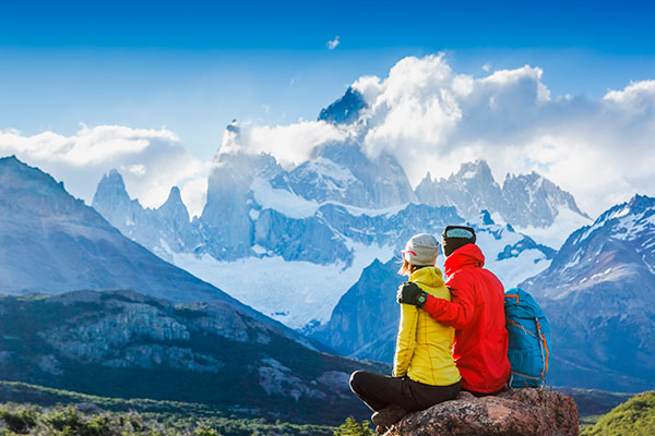 Pareja sentada en una roca mirando al Monte Fitz Roy, Patagonia argentina