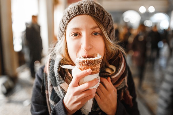 Mujer comiendo un trdelník en un lugar público en Praga, República Checa.