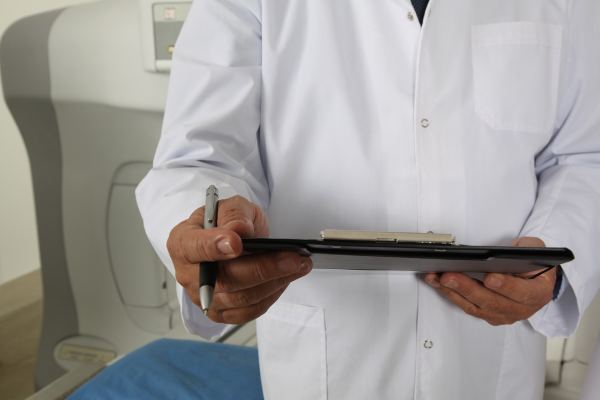 Médico segurando prancheta e caneta em ambiente hospitalar, simbolizando atendimento clínico e conta de hospital nos EUA
