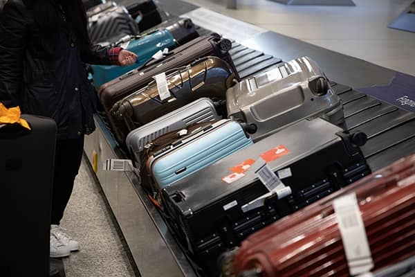 imagem de pessoa empurrando uma mala de rodinhas em aeroporto