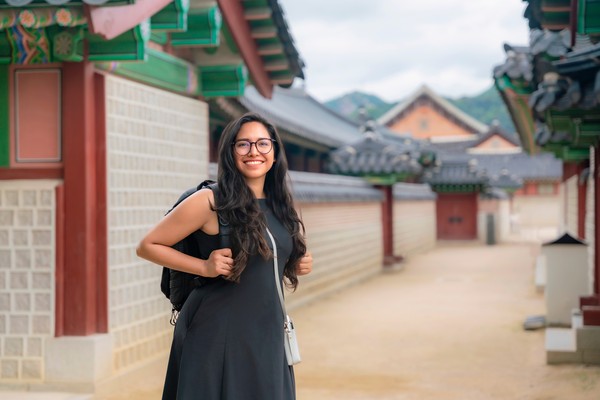 Mujer joven latina sonriendo en el patio del palacio de Gyeongbokgung, Seúl, Corea del Sur.