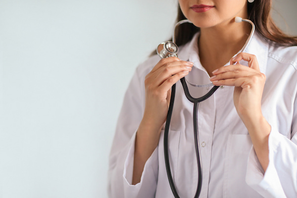 Médica sorrindo segurando um estetoscópio                  