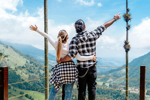 una pareja de espaldas, con los brazo extendidos y viendo al cielo