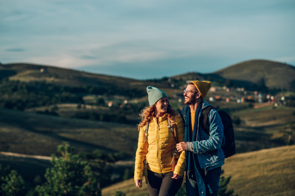 Pareja de viajeros haciendo senderismo en una ruta de montaña desconocida al atardecer.