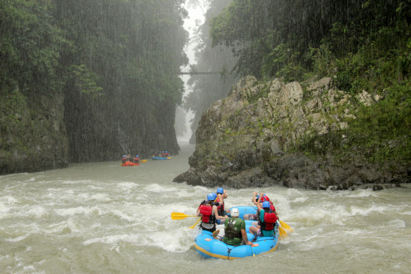 Grupo de personas haciendo rafting en el río Pacuare, Costa Rica, bajo una intensa lluvia.