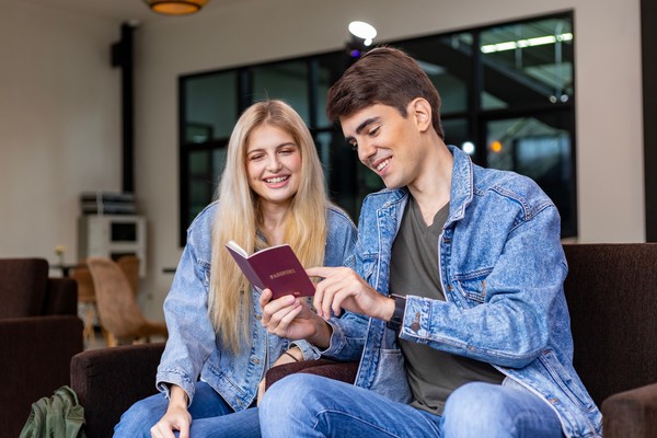 Pareja en sala de espera revisando con una sonrisa el interior del pasaporte.