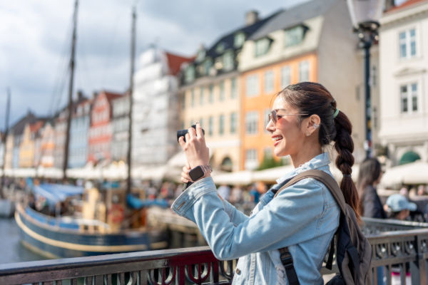 Turista tomando una foto con su celular en el canal de Nyhavn, en Copenhague.
