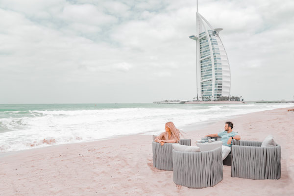 pareja sentada en unas sillas en la playa de Dubai en un día nublado.