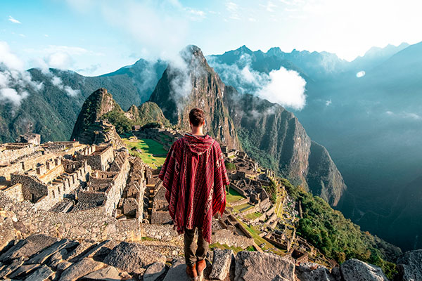 Un hombre parado en una piedra observando las ruinas de Machu Picchu.