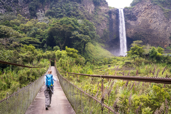 Mujer mayor caminando sobre puente en el camino a la cascada del velo nupcial, Ecuador